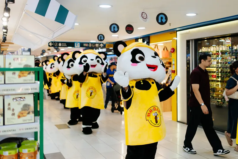 A line of PANDAi mascots waving to shoppers along a mall walkway in Kuala Lumpur, 1 August 2026