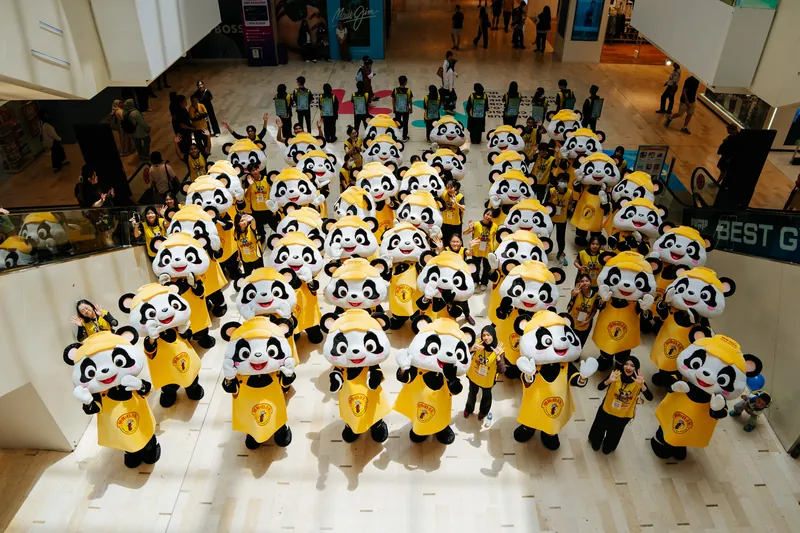 PANDAi mascots and crew waving up from a mall atrium during the Kuala Lumpur leg, 1 August 2026.