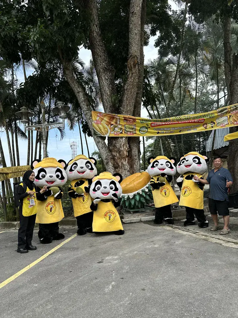 PANDAi mascots and a crew member at a durian stall in Balik Pulau, Penang, 15 August 2026