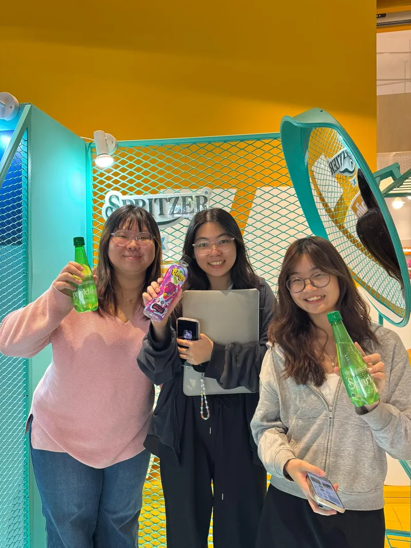 Three visitors holding Spritzer bottles at a Spritzer booth