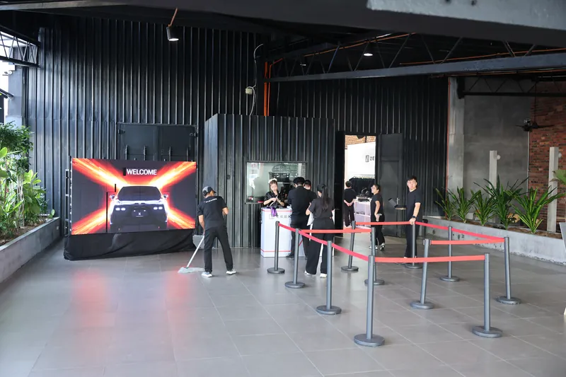Crew preparing the entrance before guests arrive, a WELCOME LED screen and red stanchion ropes, ZEEKR X launch at Odeum, JioSpace