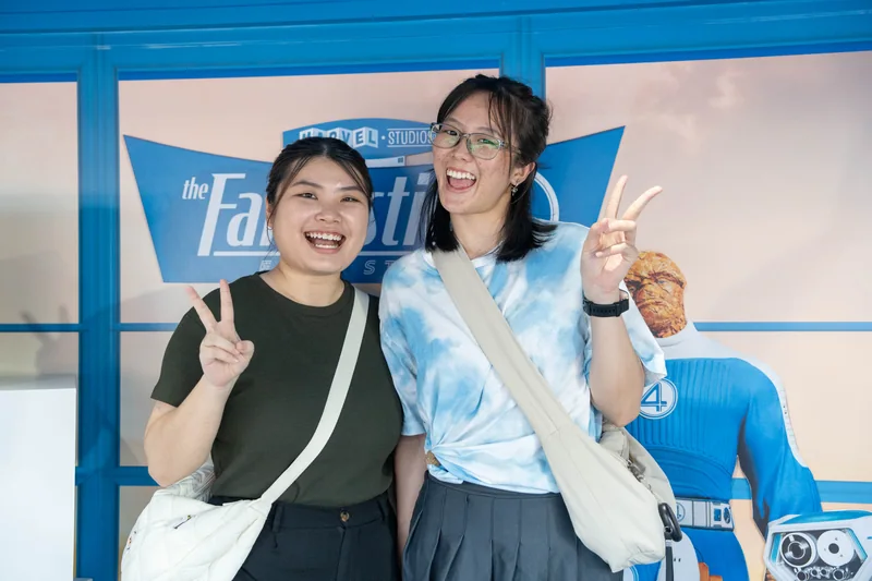 Two guests pose with peace signs in front of the Fantastic Four: First Steps backdrop inside the truck.