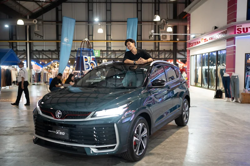 A man stands up through the sunroof of a dark X50 with its headlights on inside the B5 Street Market hall, Johor Bahru, under the B5 sign