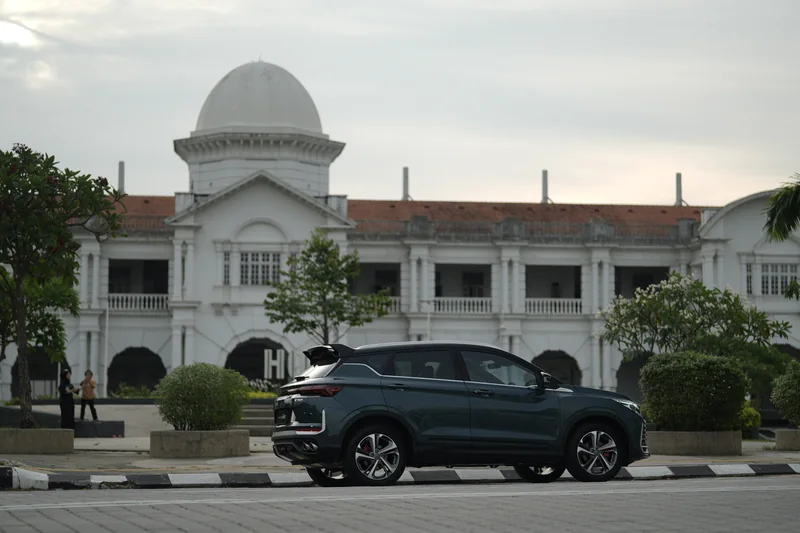A dark X50 parked in front of the white, domed Ipoh railway station building in the evening