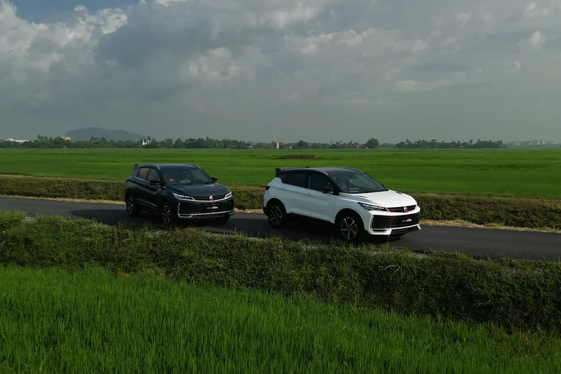 A dark and a white X50 on a narrow road between green paddy fields in Kedah, seen from above