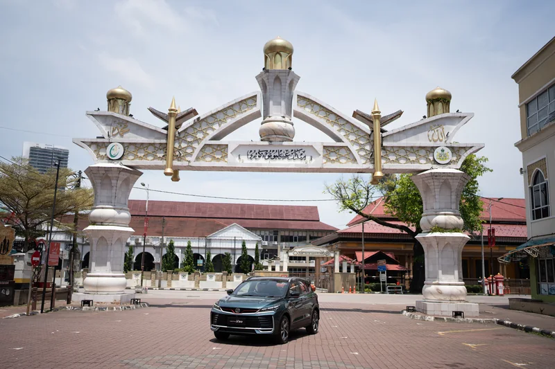A dark X50 parked beneath an ornate white arch with golden domes in Kota Bharu